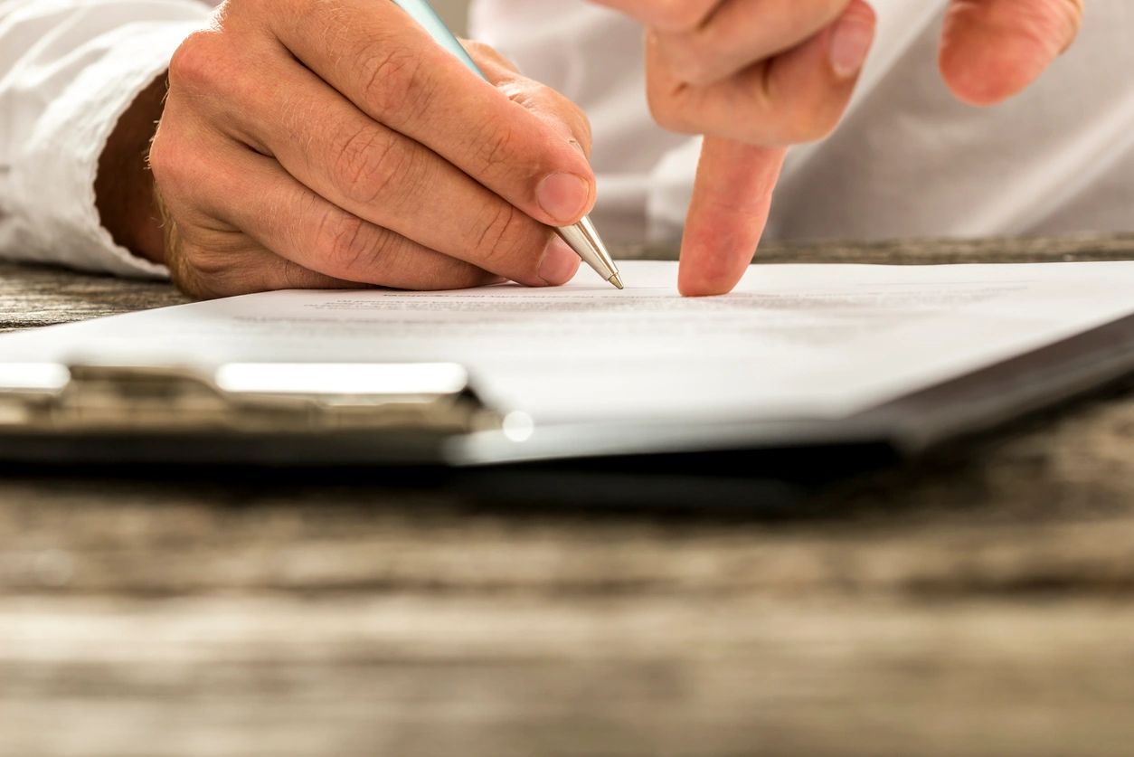 A person writing on paper with a pen.